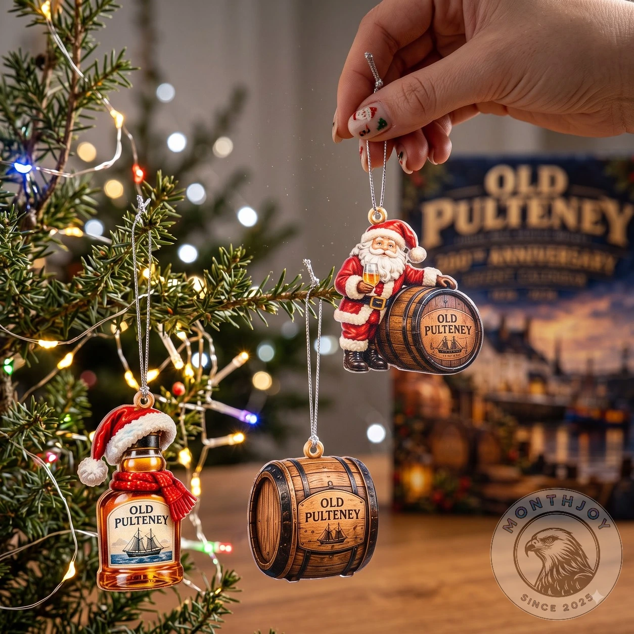 Santa-and-barrel, Old Pulteney bottle and cask ornaments hanging from a Christmas tree with the 200th Anniversary calendar box blurred in the background
