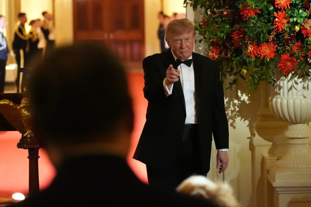 Donald Trump in a black tuxedo and bow tie, pointing toward the camera at a formal White House reception